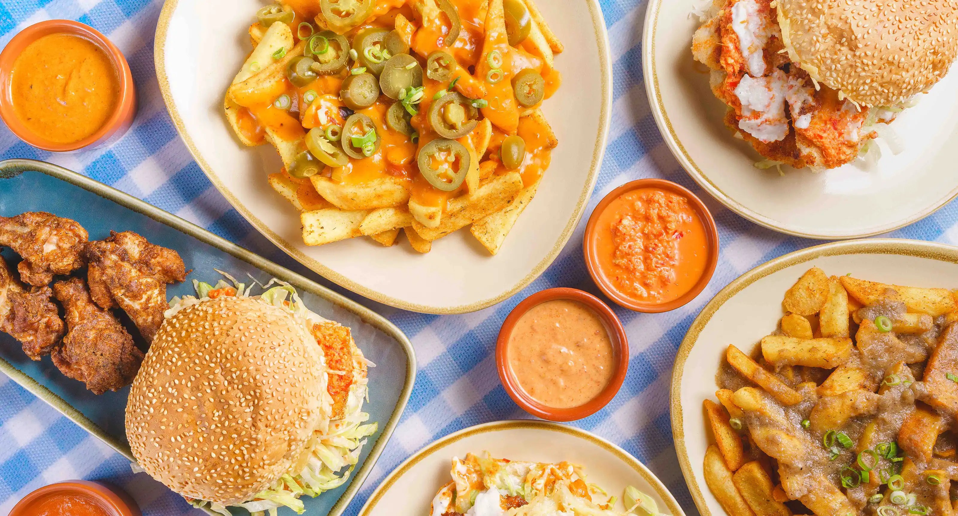 A birdeye view of Piri's menu items on a table: french fries, burgers, and hot sauces.