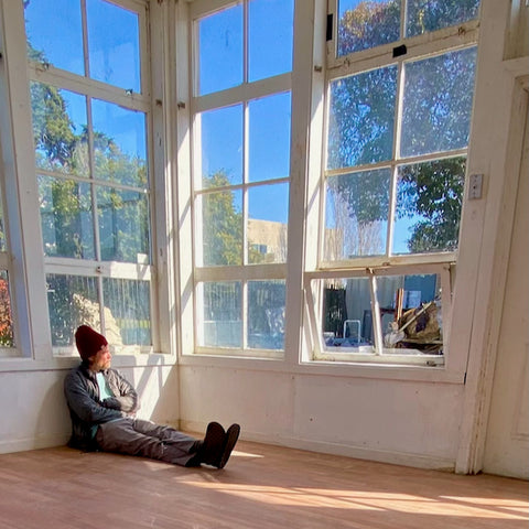 Micah sitting in the sunny window light of his new studio in Vallejo