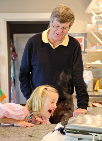 Grandfather and granddaughter making waffles