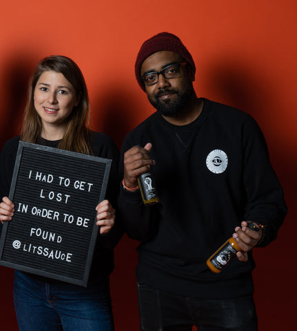 Los fundadores de Toronto Hot Sauce Company, Lost In The Sauce, sosteniendo un cartel con el identificador de Instagram @litssauce