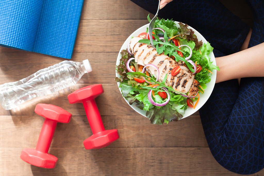 habits of health: water bottle, dumbbells and a woman holding a healthy food