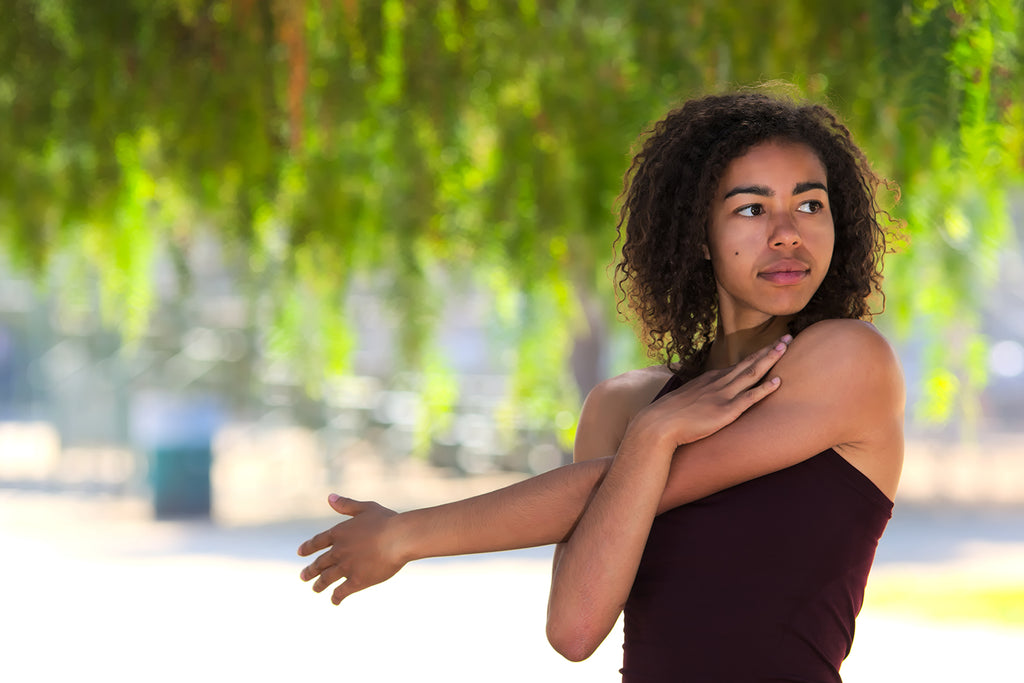 Woman stretches her arm while outdoors