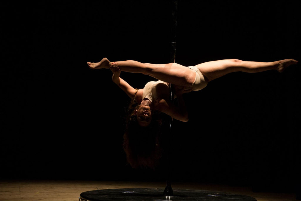 woman pole dancing in a dark studio