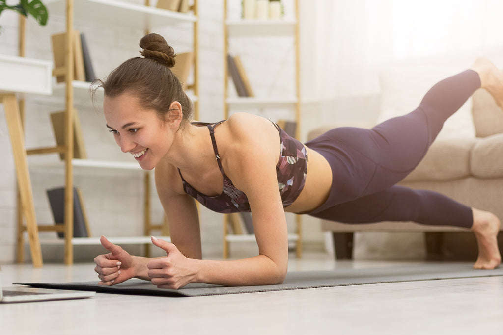 Woman doing yoga while watching online videos on her laptop