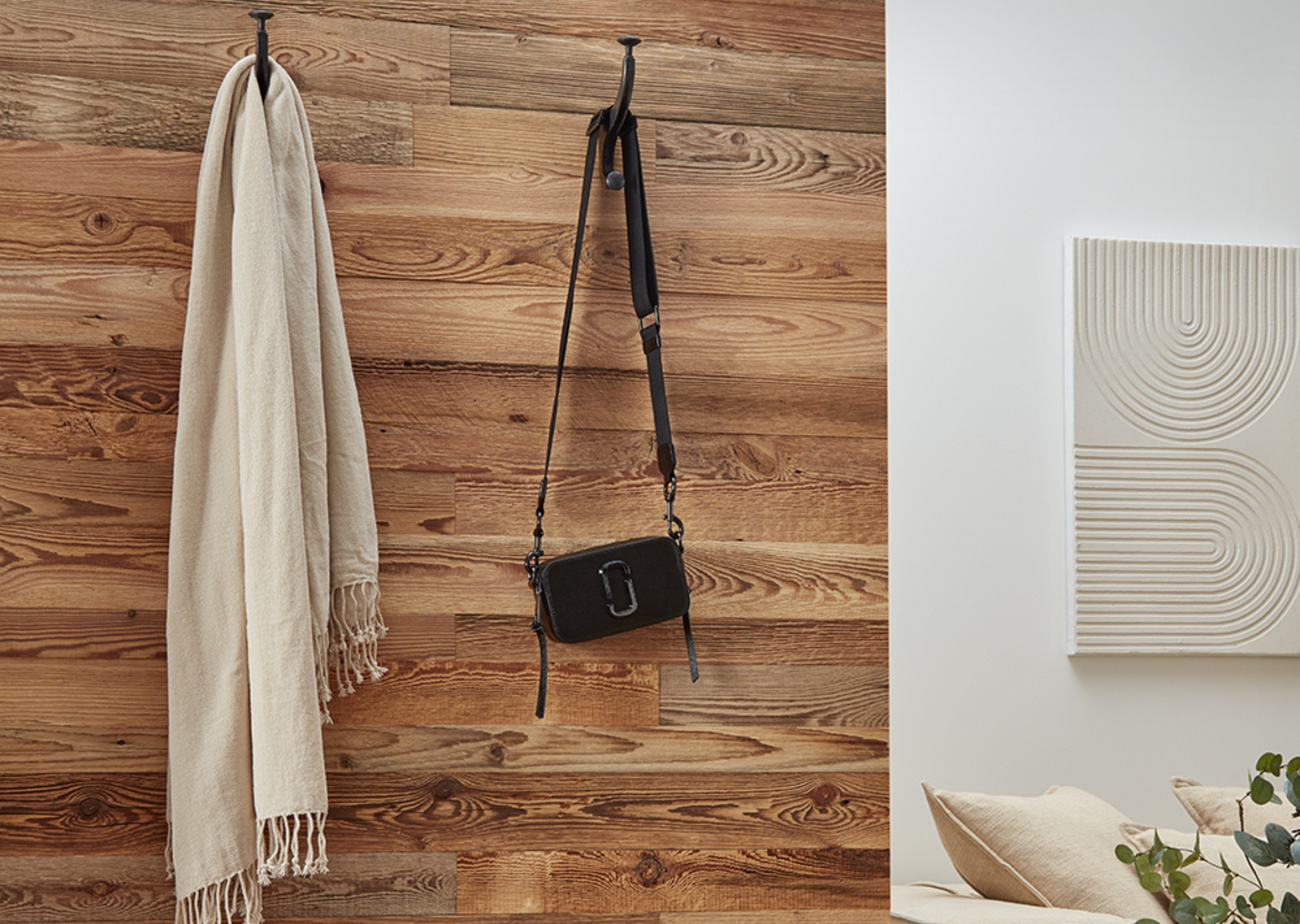 Natural Pine Reclaimed wood planks with black hooks on the wall holding a bag and scarf