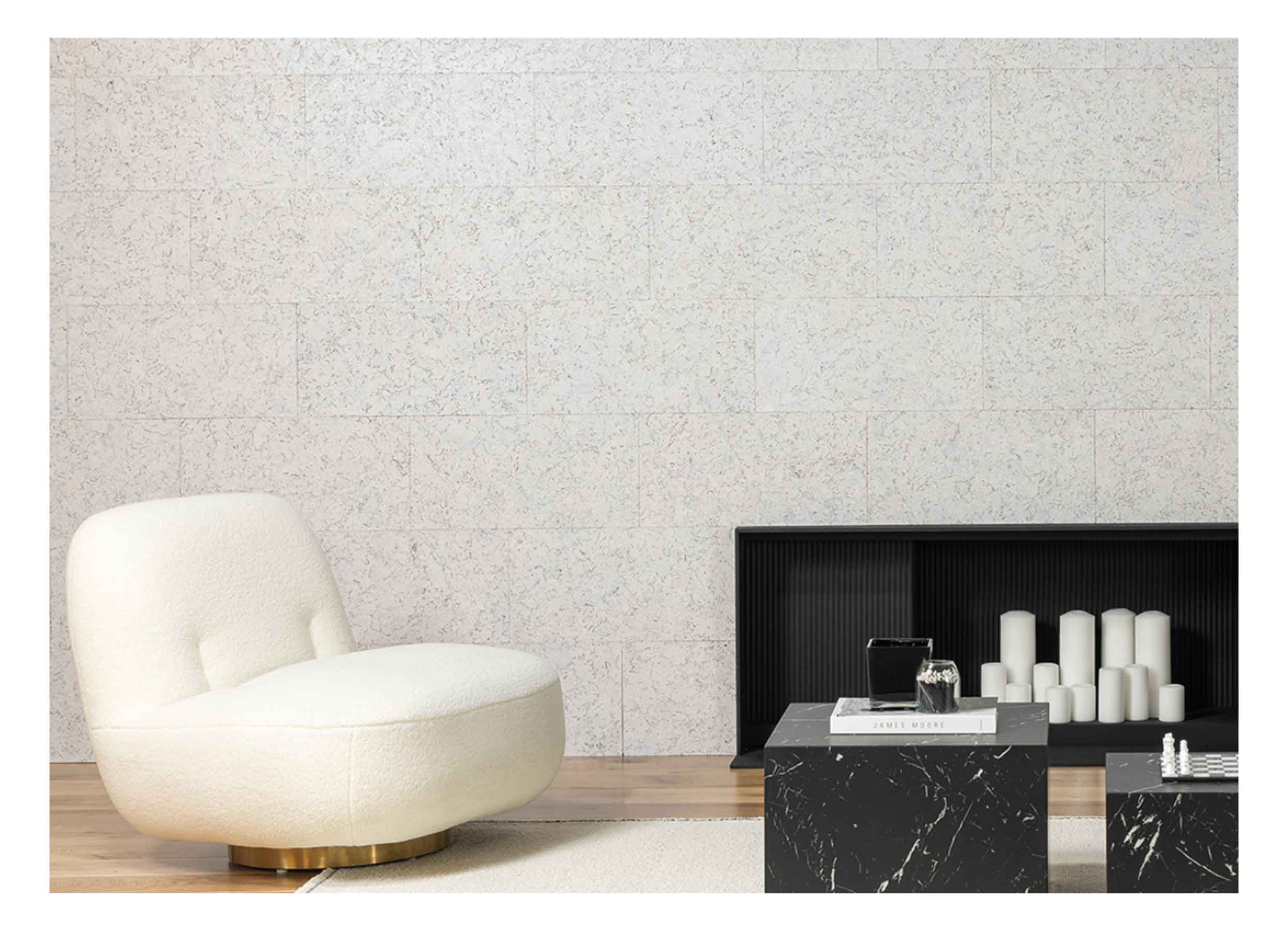 Living room with white textured CorkWall tiles, black reeded fireplace, white candles, cream chair and black marble tables.