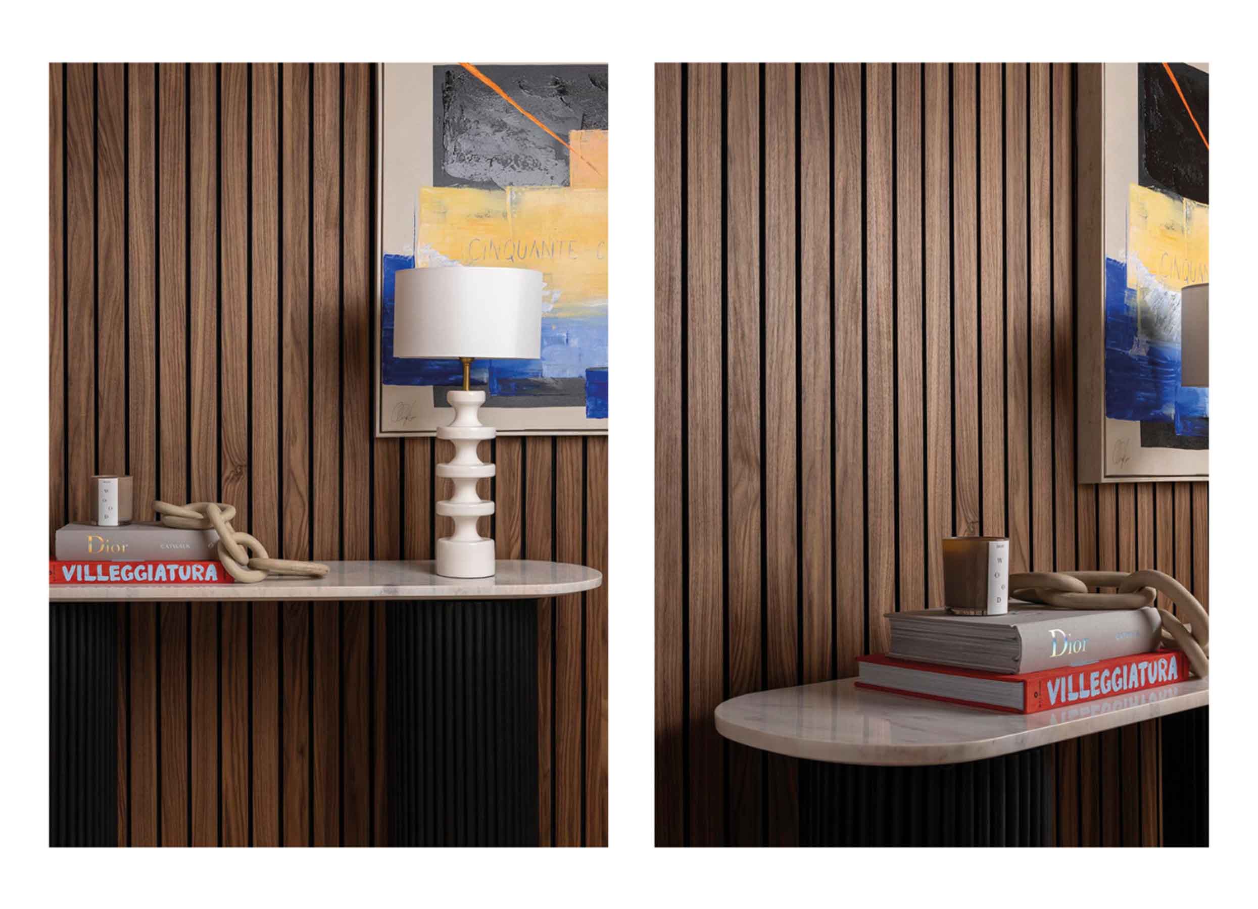 Brown slat wood panelling behind abstract wall art and a console table with books, a candle, decorative chain and white lamp.