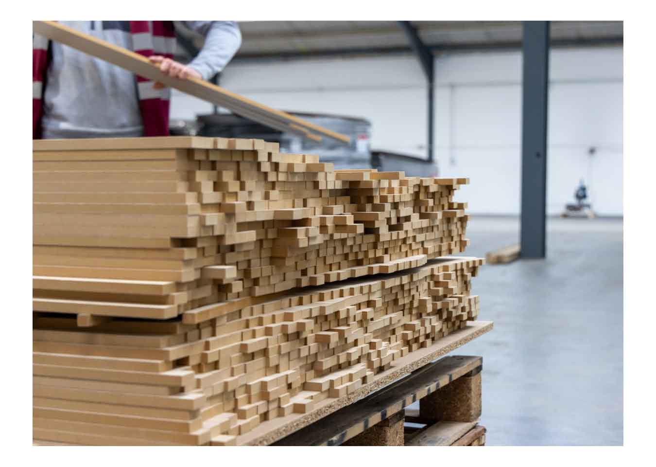 A craftsperson places wood veneer slats on a pallet in Naturewall's Yorkshire workshop.