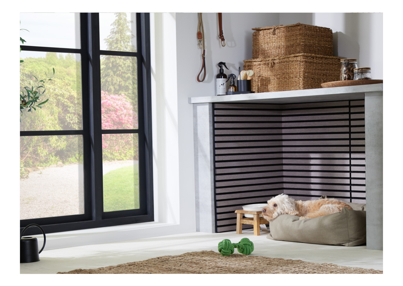 Biophilic design utility room featuring a dog lying in a bed next to SlatWall Mini Grey Oak panels and large black windows.