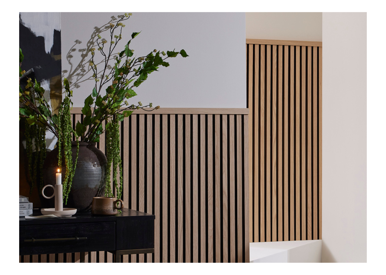 Greenery on top of a black table in front of a wall made from SlatWall Midi panels and Top Trim in Natural Oak and Black.