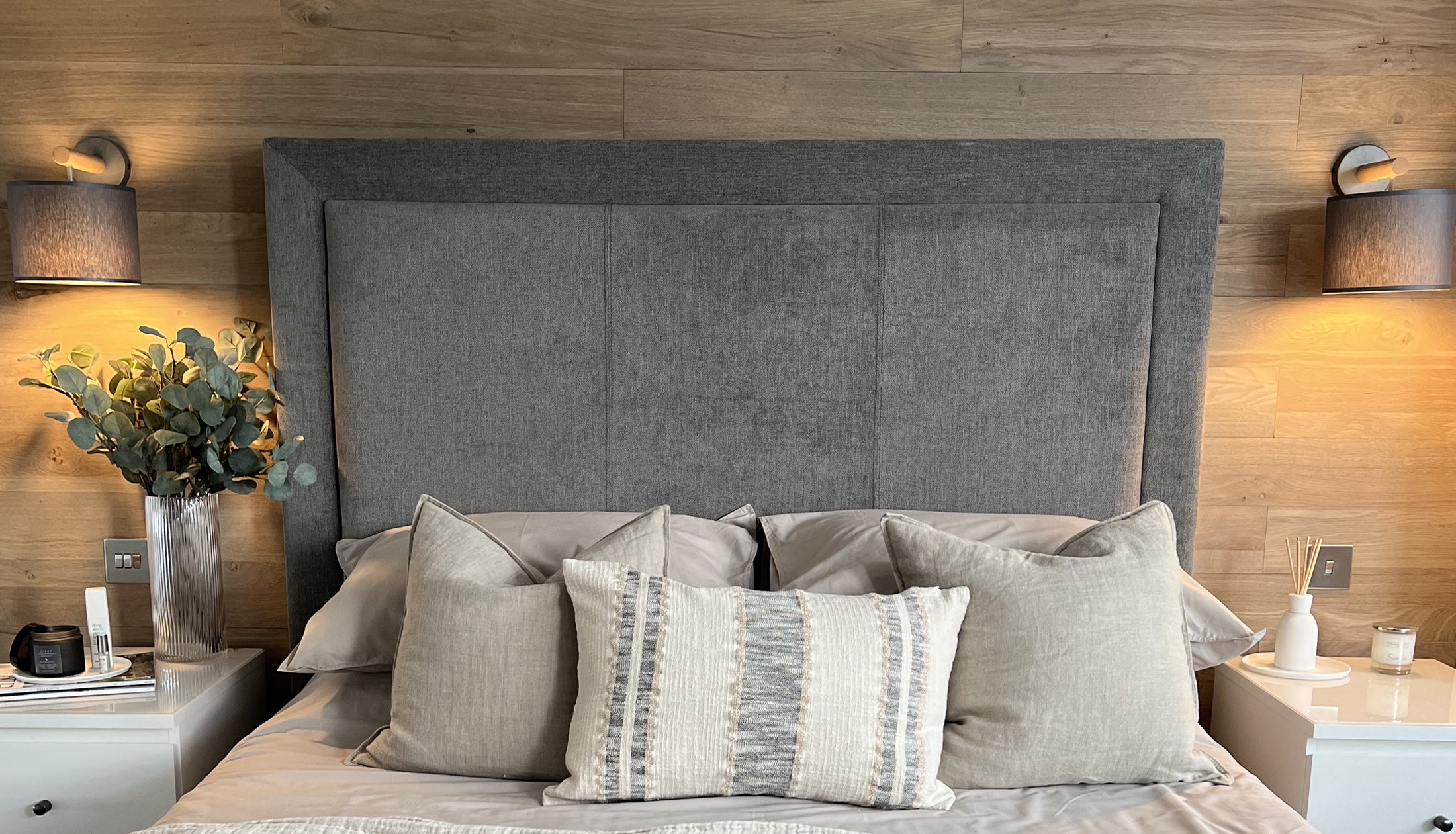 Bed with Grey headboard. Peel & Stick planks on wall. Natural coloured wood with black metal lighting to show off the golden tones.