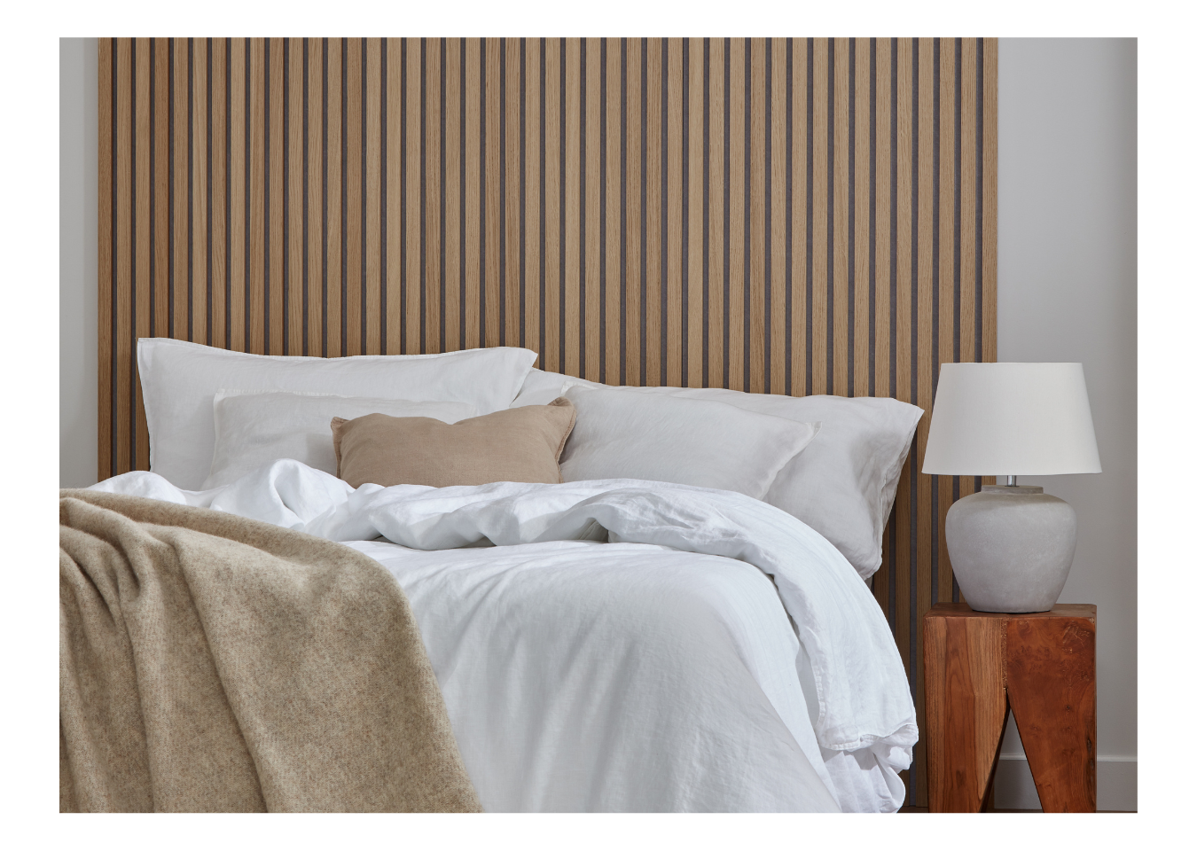 Washed Oak SlatWall behind a bed with white bedding and a side table with a lamp