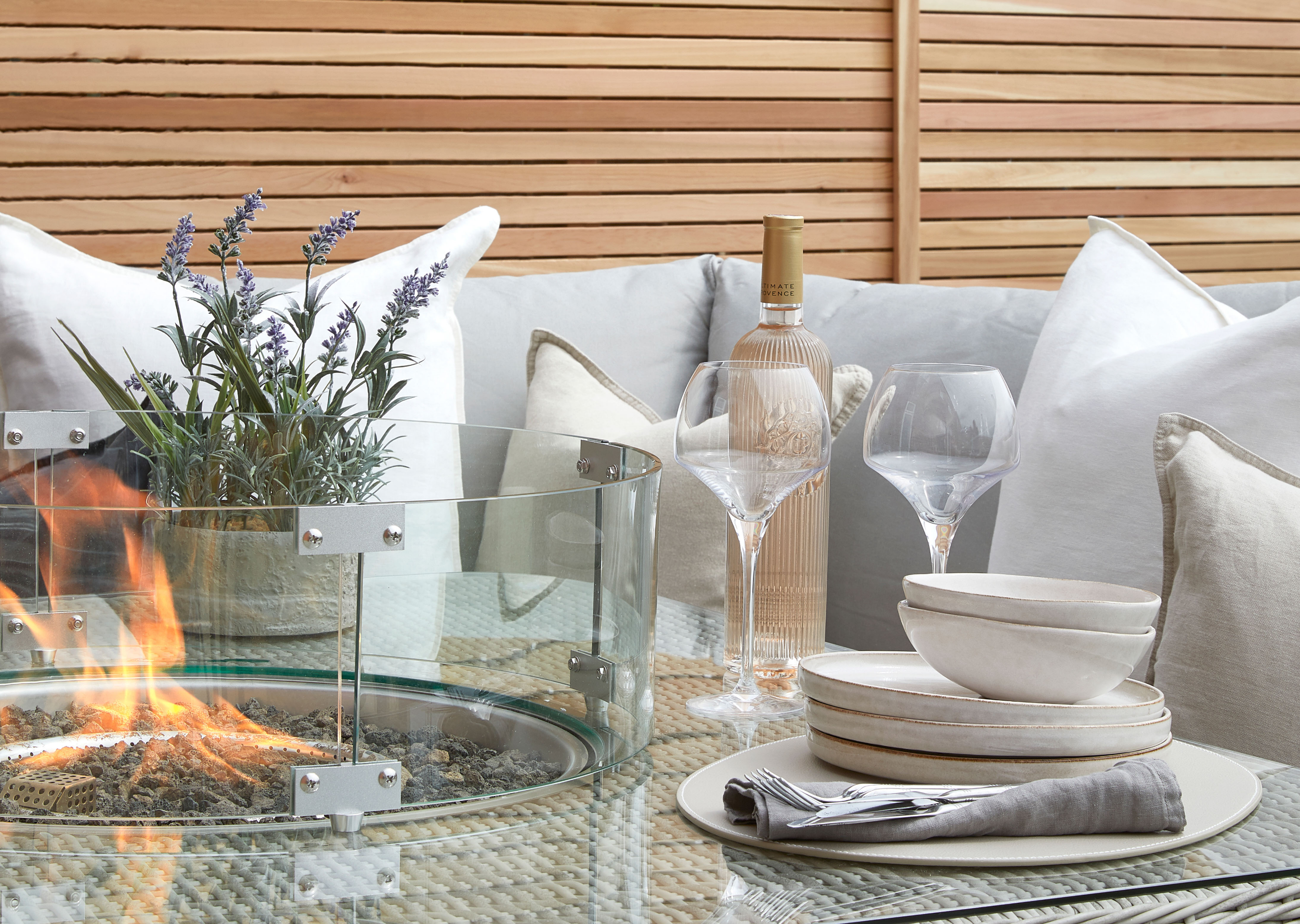 Outdoor seating area with small firepit, glasses and wine bottle. 