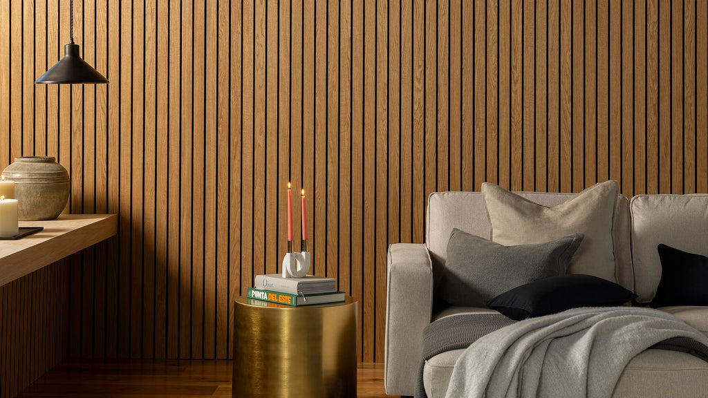 Contemporary living room featuring SlatWall Grand Oiled Oak panels, styled with a neutral sofa, candles, books and ceramics.