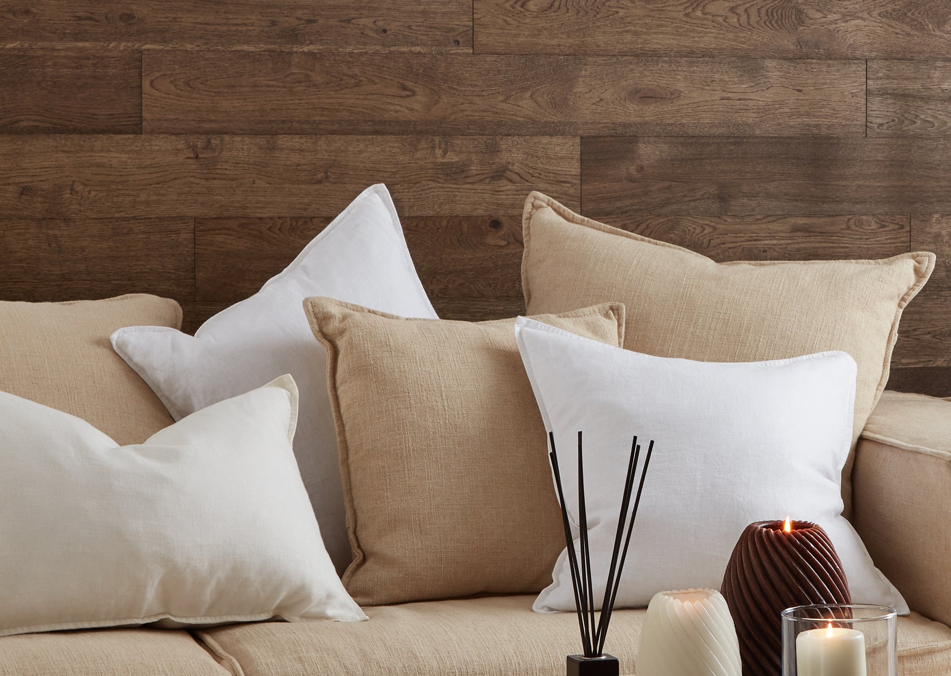 Dark brown Naturewall Self-adhesive panels in background. Beige sofa with cushions in foreground.