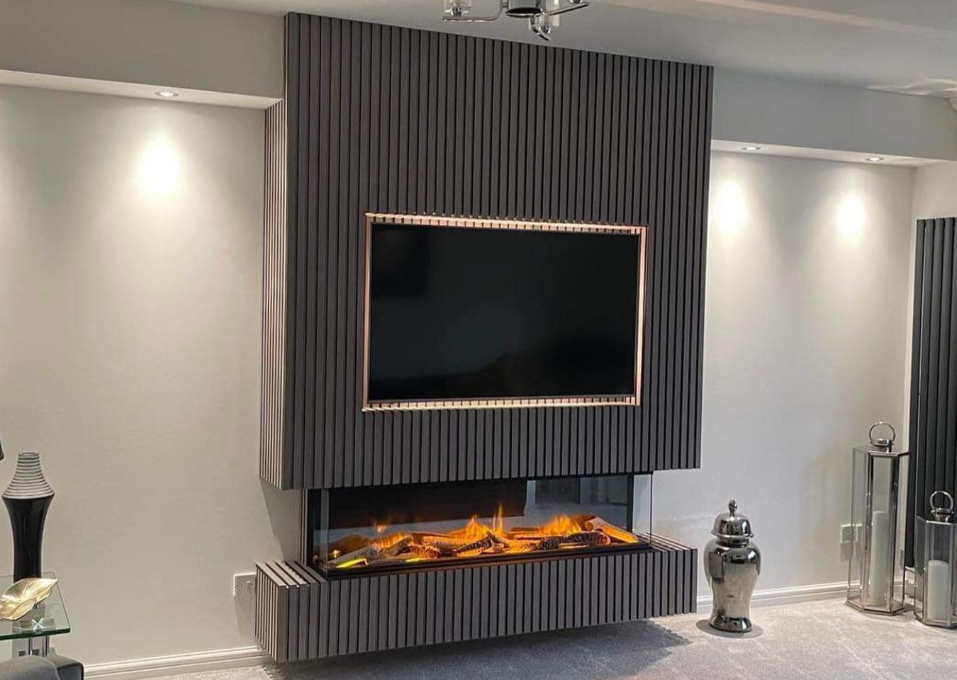 Slatwall grey oak on chimney breast with tv mounted on the wall. Contemporary fire beneath