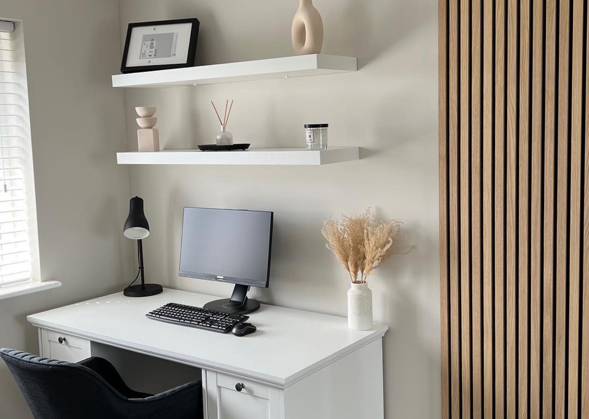 Work from home office space. White desk with white shelves above. Naturewall Slatwall panel on the wall to the right.