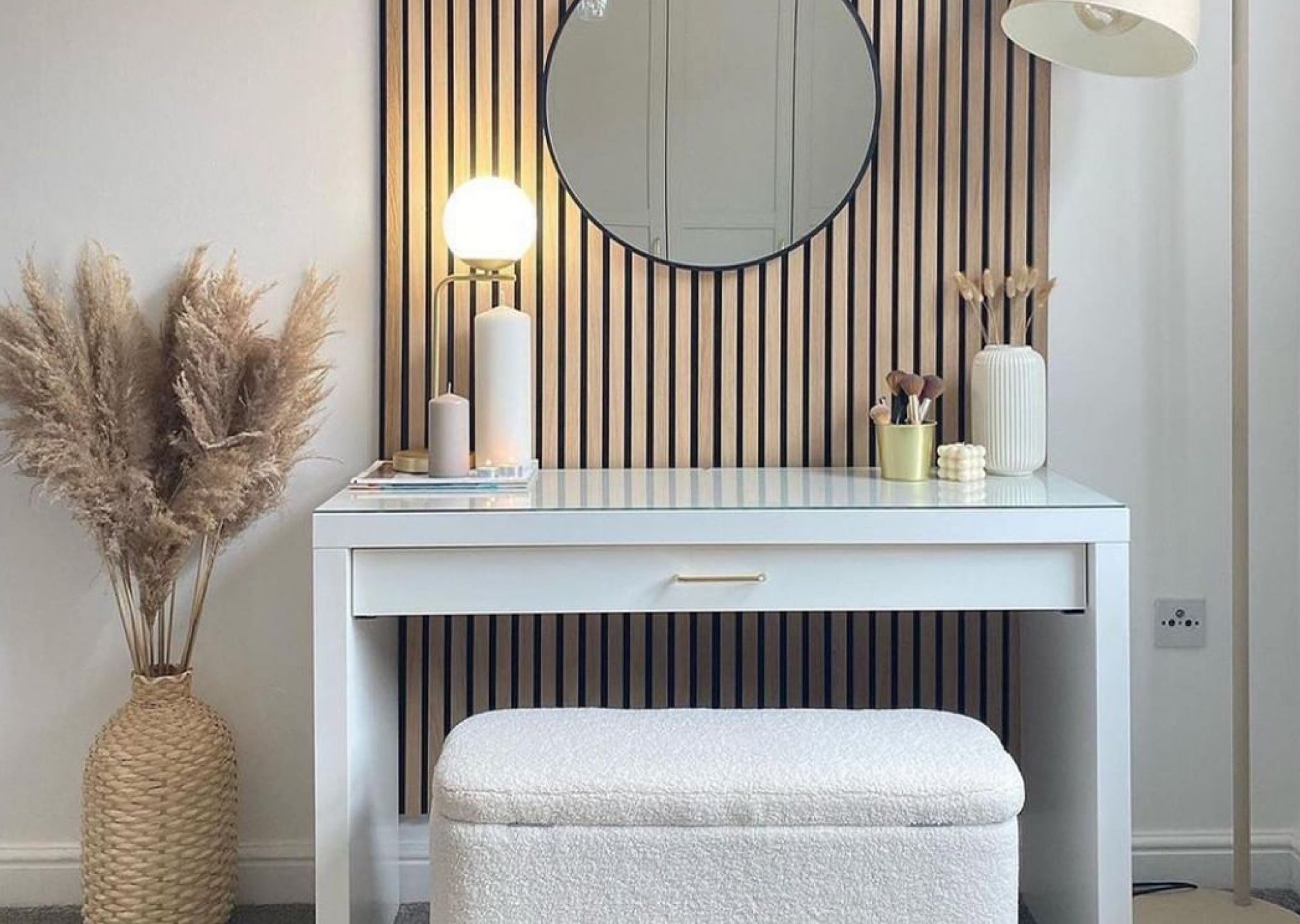 White desk used as a vanity space in a home. Naturewall slatwall panel on the wall behind with a hanging mirror