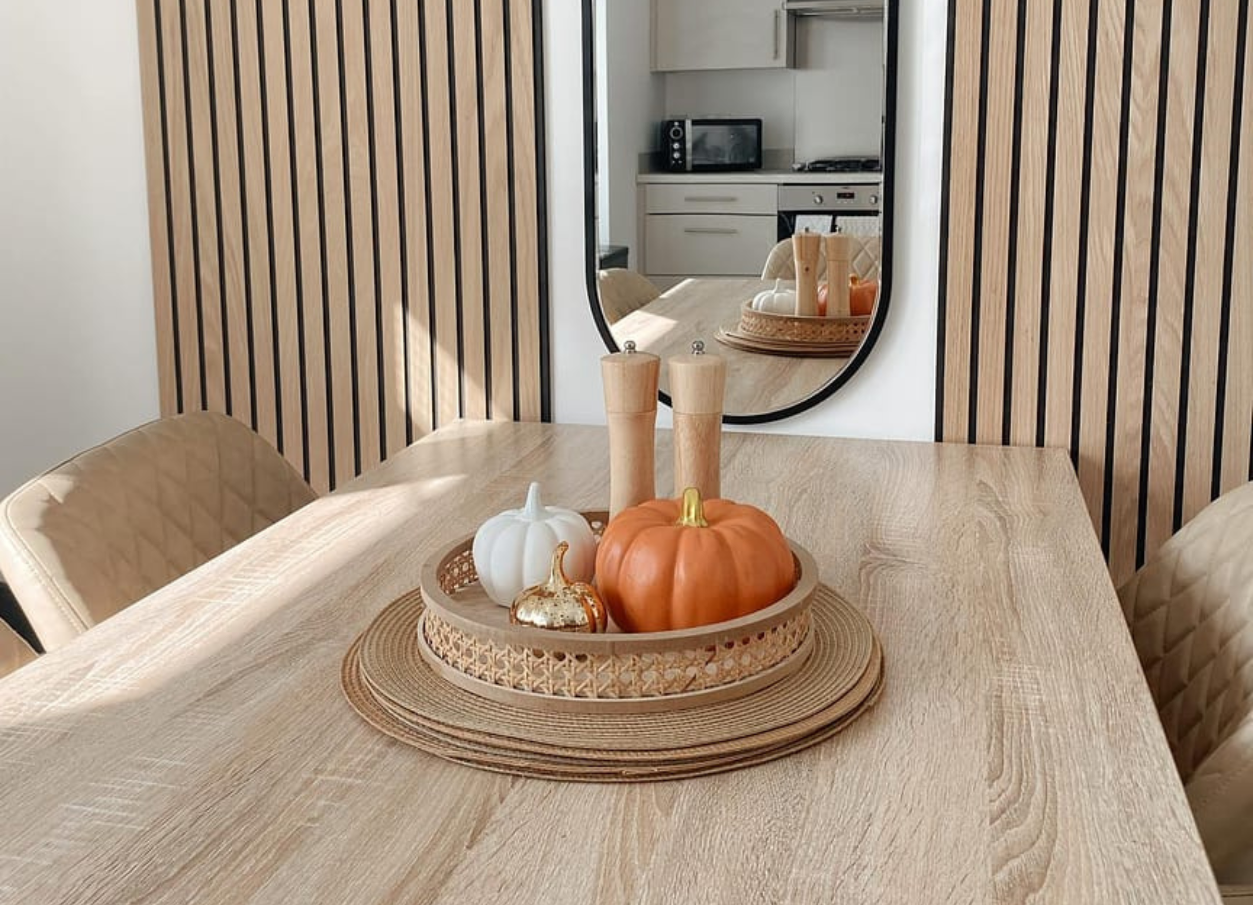 Table with pumpkins and candles in the centre. Slatwall panels on the background will with an oval mirror between the two wood panels.