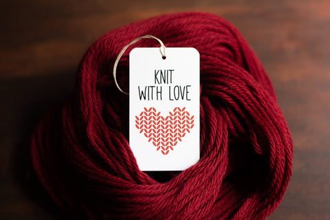 Knit with love gift tag sitting in a pile of red yarn