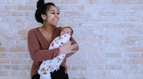 a mom holding her swaddled baby in her arms