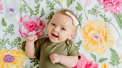 smiling baby lying on a floral swaddle blanket