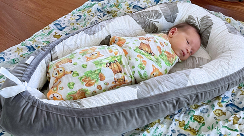 a baby swaddled in kloud bambu woodland muslin swaddle blanket