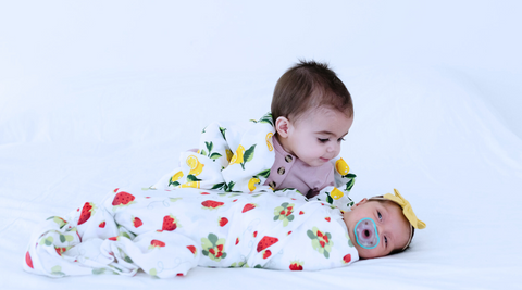 two babies wrapped in kloud bambu muslin swaddle blanket in lemon and strawberry print