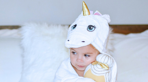 baby holding her doll while wrapped in kloud bambu white unicorn hooded bath towel