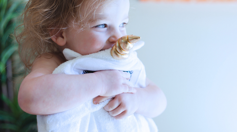 a baby girl hugging her kloud bambu white unicorn bamboo hooded towel holiday gift