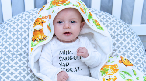 a baby wrapped in woodland hooded towel after bath