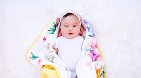 a baby girl lying with her kloud bambu minky peony flower bamboo blanket