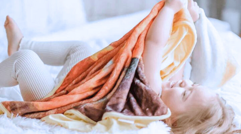 girl child lying on bed with squirrel minky bamboo blanket for fall season