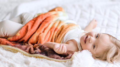 baby girl lying on bed with her kloud bambu squirrel minky blanket