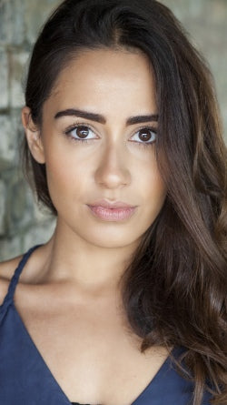 ITV Star Laila Zaidi Portrait Shot In Blue Top Against Brick Wall