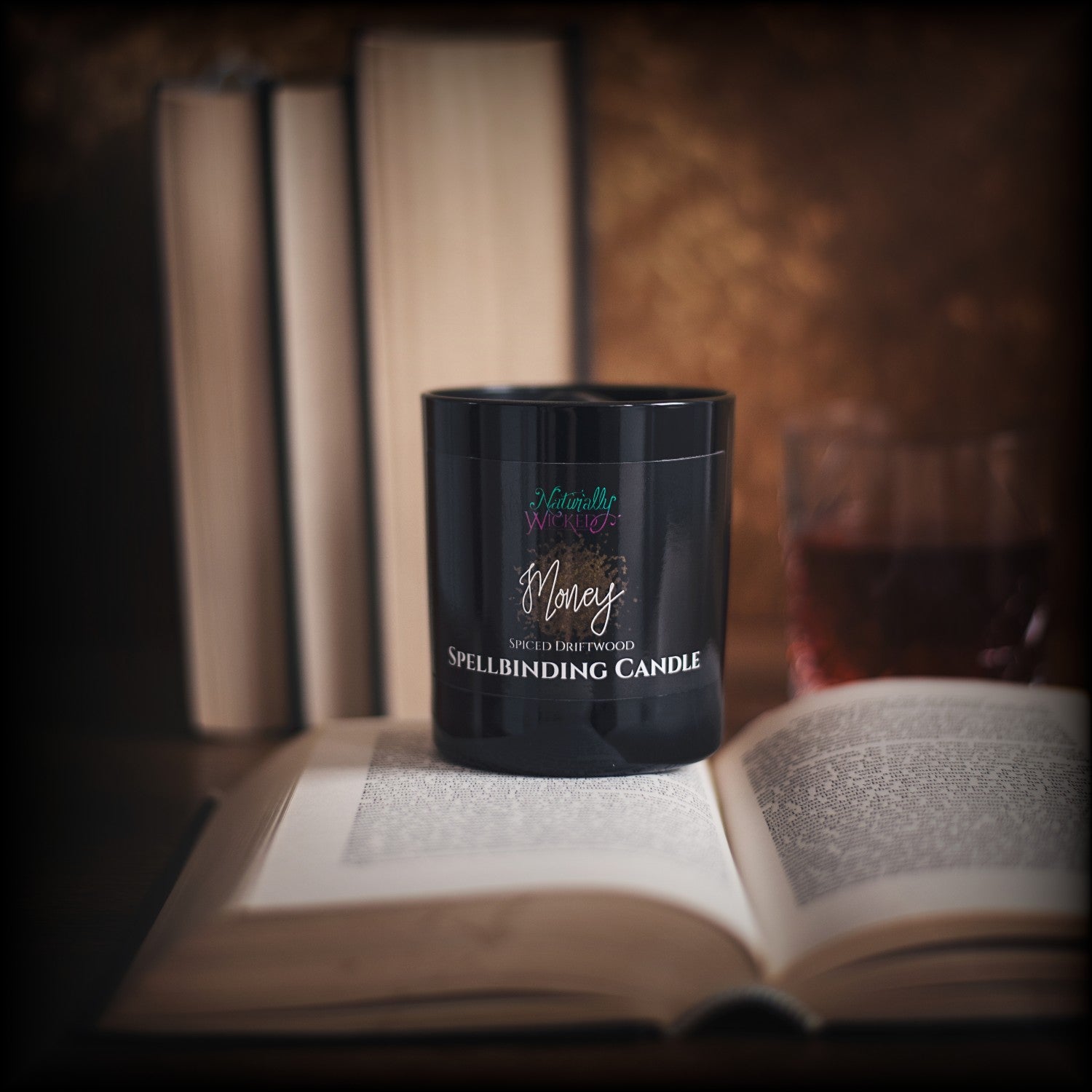 Naturally Wicked Spellbinding Money Spell Candle Entombed With Black Onyx Crystal Sits on Sophisticated Book Aside Whiskey Glass