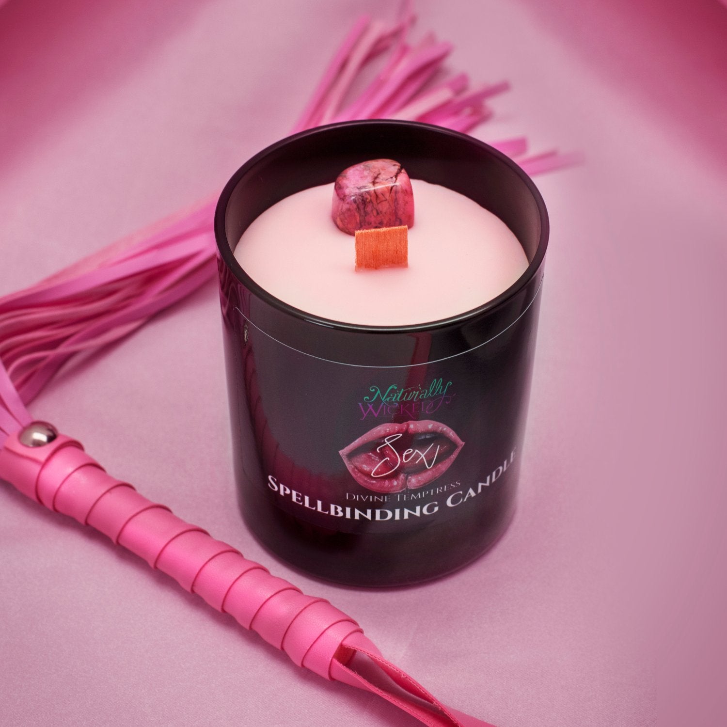 Naturally Wicked Spellbinding Sex Spell Candle Entombed With Rhodonite Crystal Sits Amongst Kinky Pink Whip
