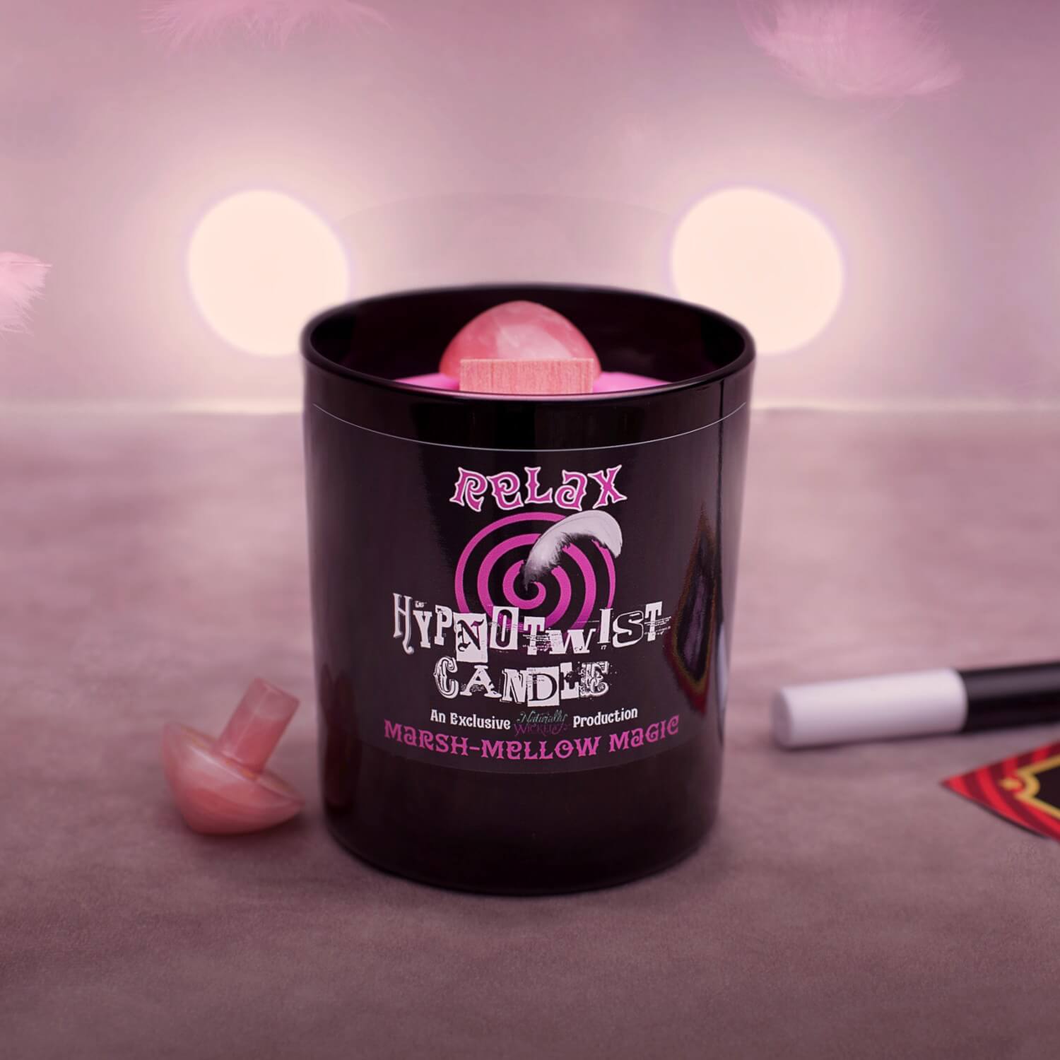 Naturally Wicked Hypnotwist Relax Candle Entombed With Hypnotic Crystal Spinning Top Beside Drifting Pink Feather