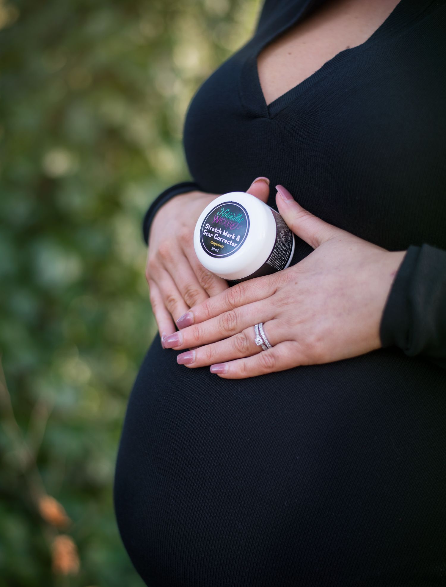 Naturally Wicked Pregnant Mamma In Black Dress Resting Naturally Wicked Stretch Mark & Scar Corrector On Baby Bump