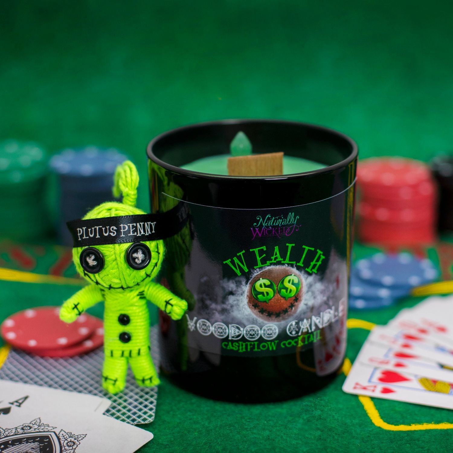 Naturally Wicked Voodoo Wealth Candle On Green Casino Table Amongst Green Voodoo Doll, Poker Chips & Playing Cards