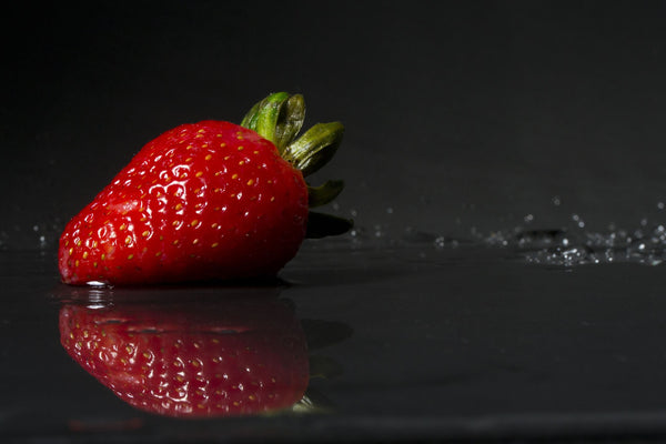 Strawberry slashing in water on dark background