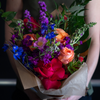 Summer bouquet of seasonal stems in bright colors of magenta, peach, blue, and purple