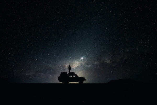 silhouette of off-road car with man on top during night