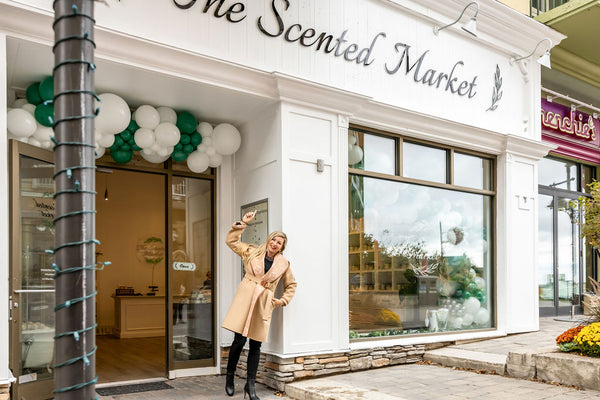Founder and CEO of The Scented Market Kristy Miller stands in front of her new Scented Market store in the Blue Mountain Village. She is pointing up at the store's sign above her.