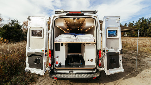 Ford Transit RV Camper Van with the rear doors open showing a cargo sliding tray and roof rack