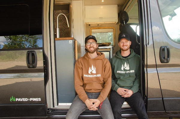 van conversion company owners sitting in the door of a ram promaster motorhome