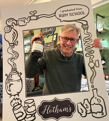 Rum School Graduate holding a sign and their own made rum recipe