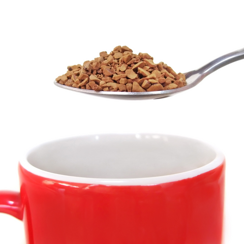 instant coffee on a teaspoon about to be poured into a red mug