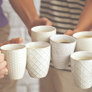 group of people holding mugs of coffee together