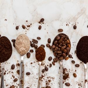 top view of metal spoons with different kinds of coffee of varying levels of grind